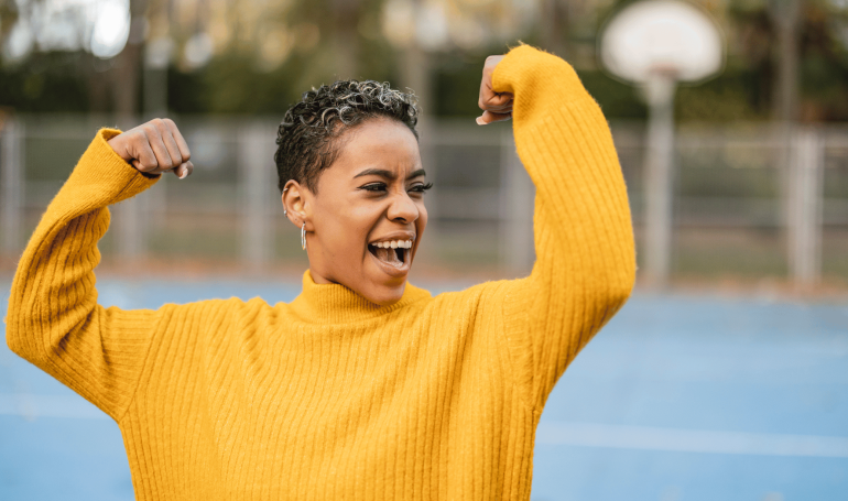 Woman smiling and flexing her arms with excited expression.