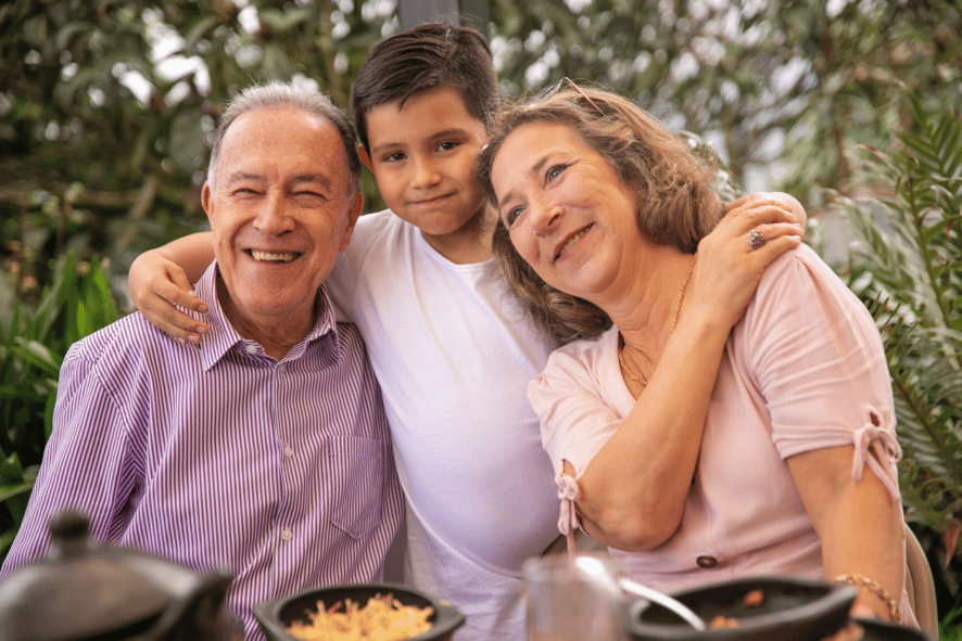 Two grandparents sitting on either side of a young boy, all smiling.