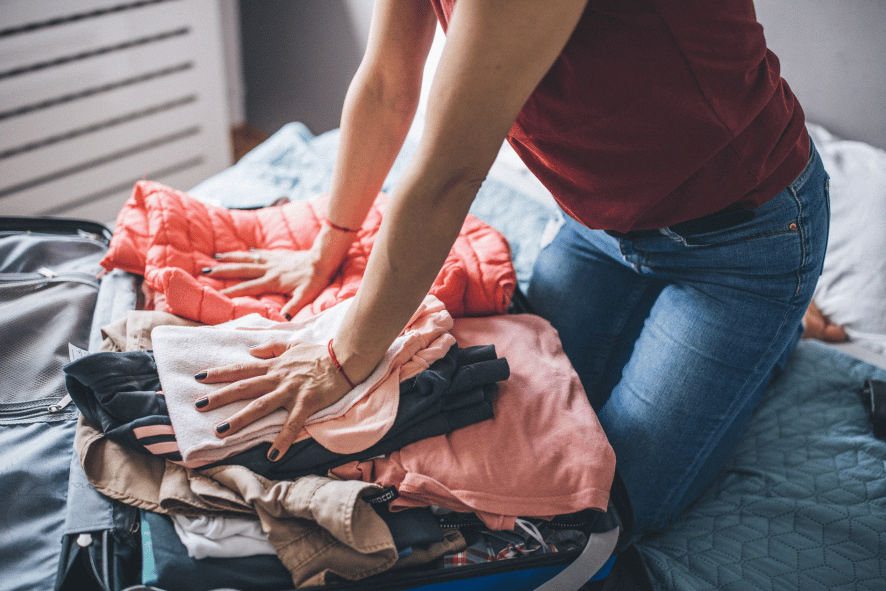 Woman packing suitcase with clothing.